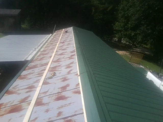 Old rusted panels beside newly installed green metal roofing — Wind Damage Roof Repair by Roofing Brothers in Deer Creek