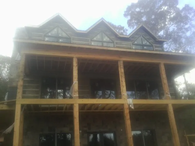 Dormers and porch framing on a large log home under construction — Roof Coating work by our crew in Deer Creek