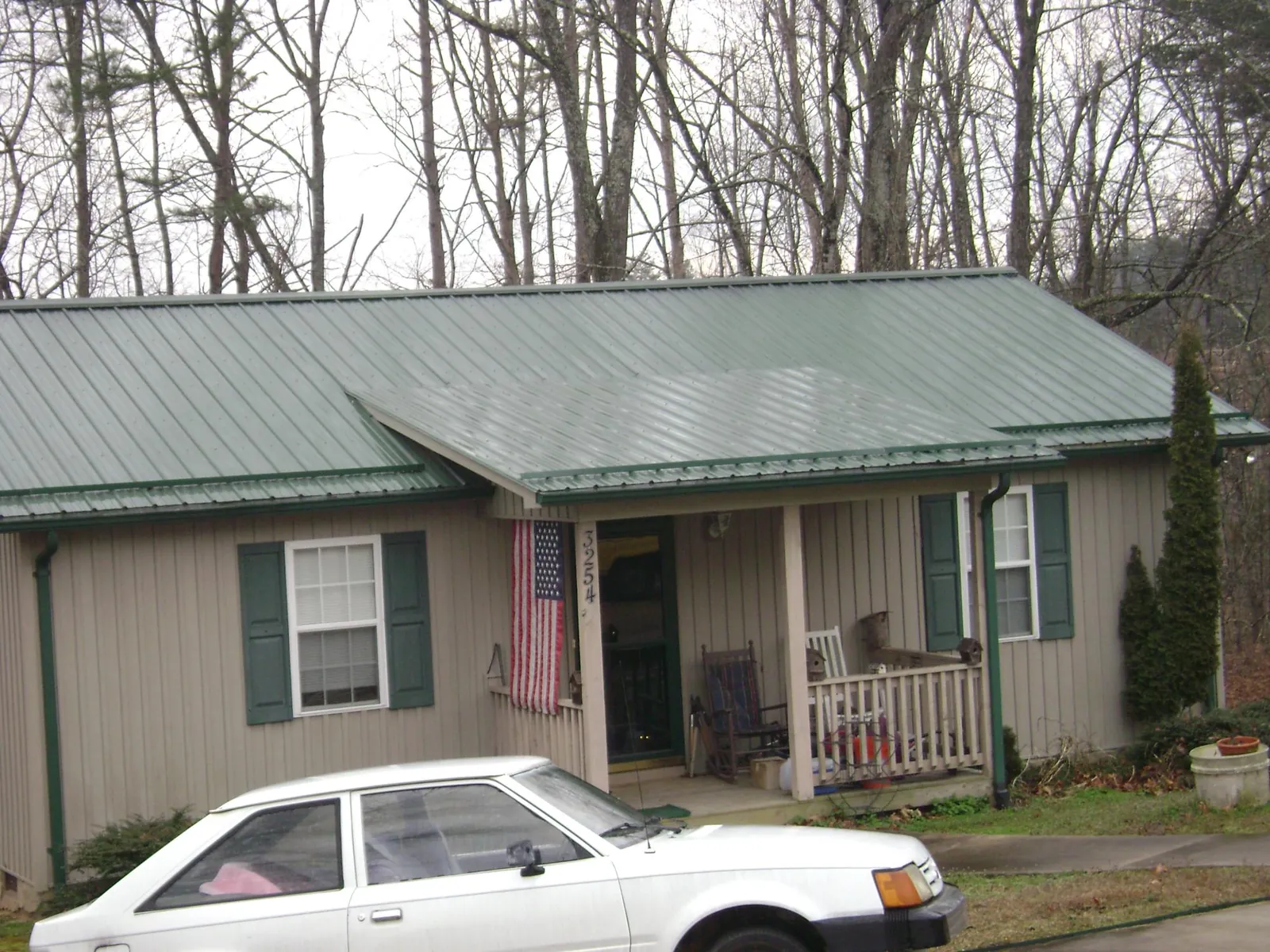 Green metal roof and front porch on a tan sided cottage in Deer Creek